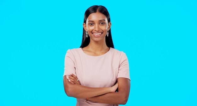 Foto sonrisa confiada y retrato de mujer con los brazos cruzados emocionada orgullosa y aislada en un estudio de fondo azul la confianza del líder y la mujer con una mentalidad positiva se relajan, la persona tranquila y feliz