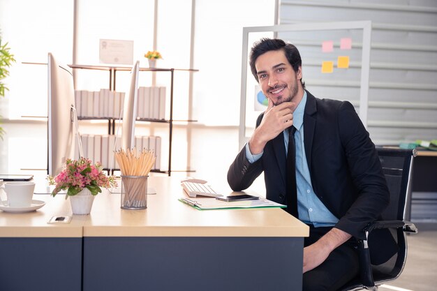 Sonrisa de empresario durante el trabajo con la computadora en la oficina