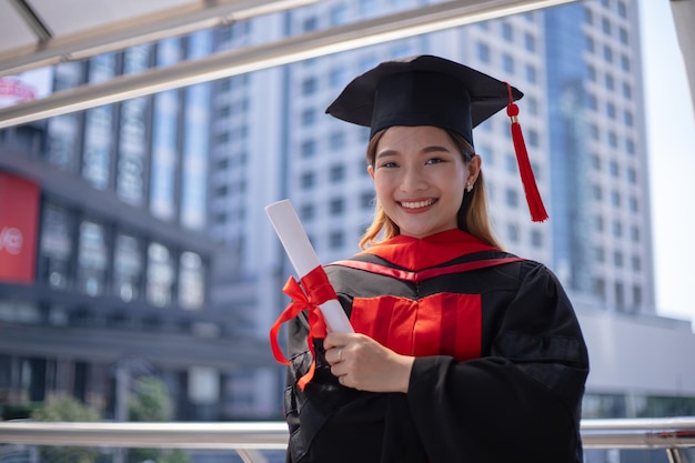 Sonrisa estudiante asiático graduado mano sosteniendo diploma