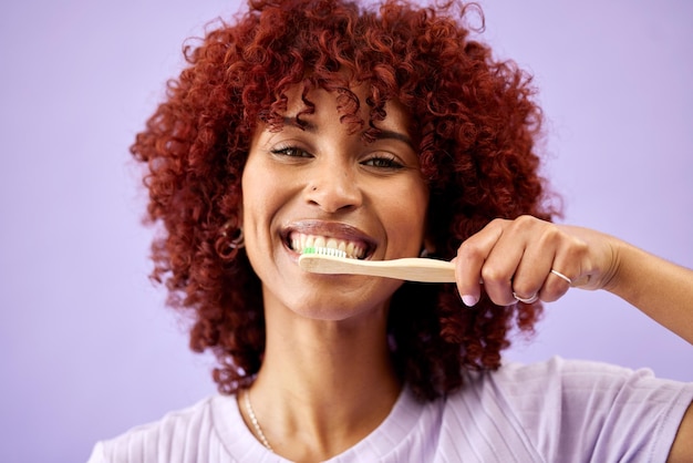 sonrisa facial y mujer cepillándose los dientes con bambú en un estudio aislado sobre un fondo púrpura retrato cepillo de dientes de madera y persona feliz limpieza para higiene ecológica salud dental o sostenibilidad