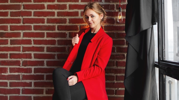 Sonrisa feliz empresaria usar chaqueta roja - mujer de negocios sobre pared de ladrillo de oficina