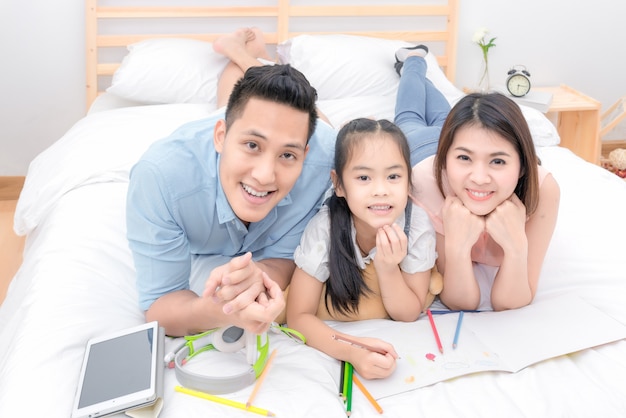 La sonrisa feliz de la familia asiática y se relaja en cama en casa en vacaciones del día de fiesta.