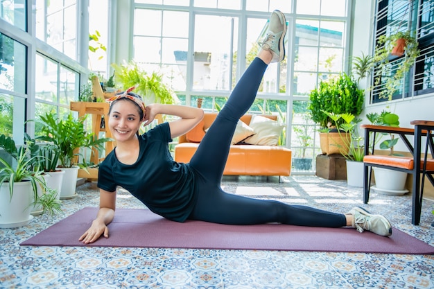 Sonrisa feliz Hermosa mujer asiática joven estirando ejercicio entrenamiento en casa