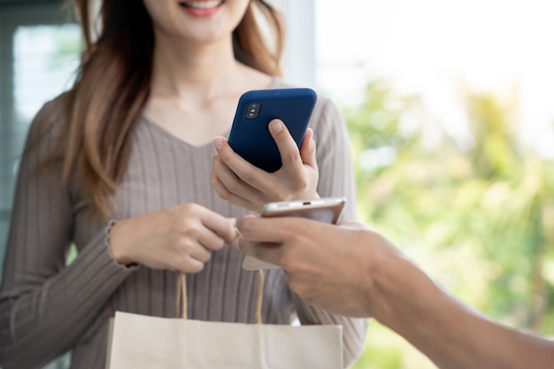 Sonrisa feliz Mujer asiática escanear código QR para pagar comida Repartidor enviar entregar tienda en línea express contenedor de papel comida para llevar cartero servicio de entrega paquetes dinero electrónico Transferencia digital