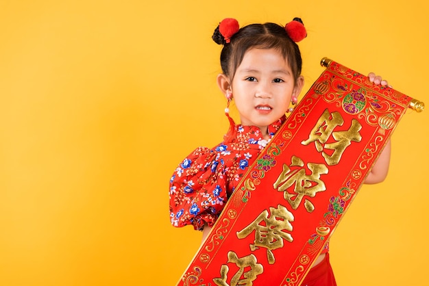 Sonrisa feliz de la niña pequeña china asiática que lleva el qipao rojo del cheongsam Pareados del festival de primavera