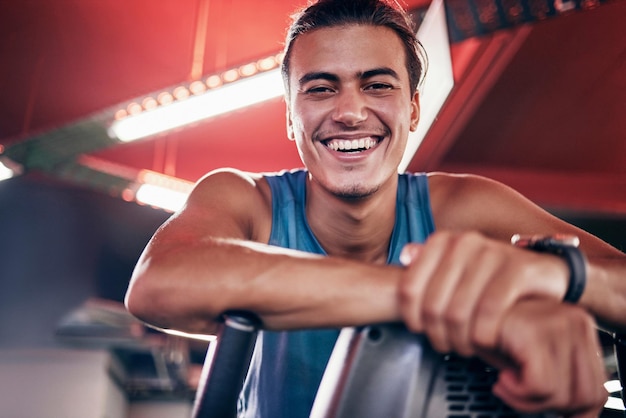 Sonrisa de fitness y retrato del hombre en la felicidad del gimnasio en el ejercicio de entrenamiento con equipo en el estudio Entrenador personal feliz o entrenador con sonrisa en la cara motivación y relajación en el descanso en el entrenamiento deportivo