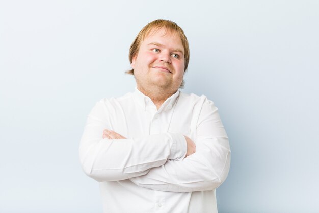 Sonrisa gorda del hombre auténtico joven del pelirrojo confiada con los brazos cruzados.