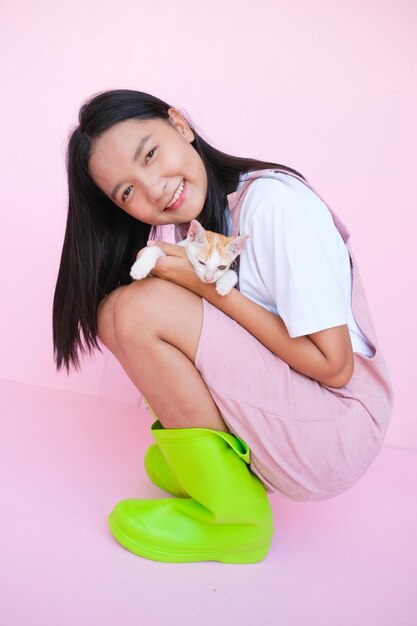 Sonrisa joven con gato sobre fondo rosa