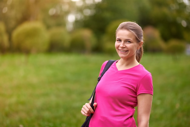 Sonrisa joven en ropa deportiva de pie en el parque