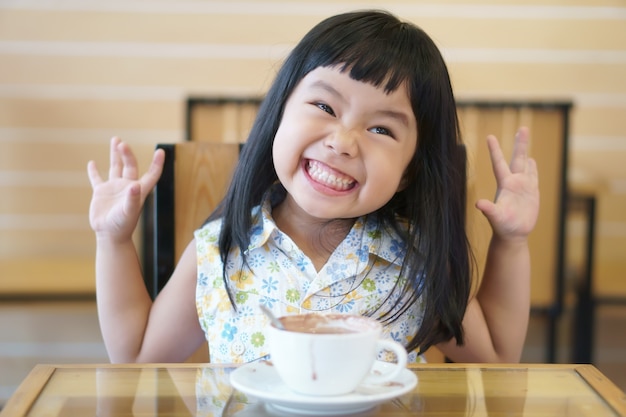 sonrisa linda de los niños o del niño del niño y bebida deliciosa caliente del cacao o del chocolate