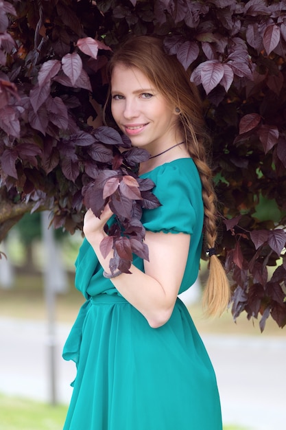 Sonrisa linda pelirroja de la mujer en retrato púrpura de las hojas