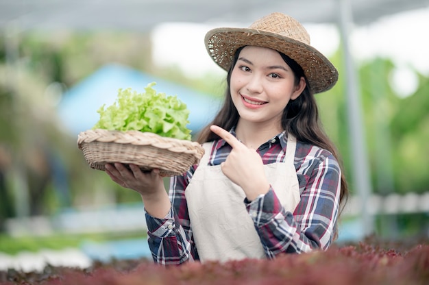 Sonrisa de mujer asiática joven cosechando verduras de su granja hidropónica