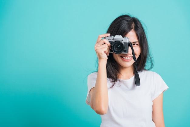 Sonrisa de mujer asiática de pie con cámara de fotos sin espejo