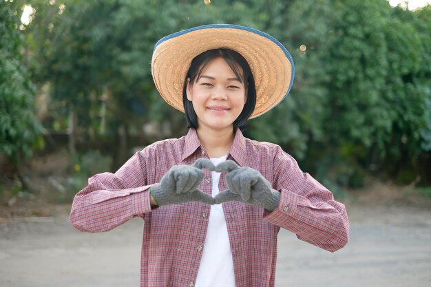 Sonrisa de mujer campesina asiática y manos de símbolo de corazón