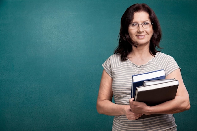 Sonrisa mujer maestra con libros sobre fondo