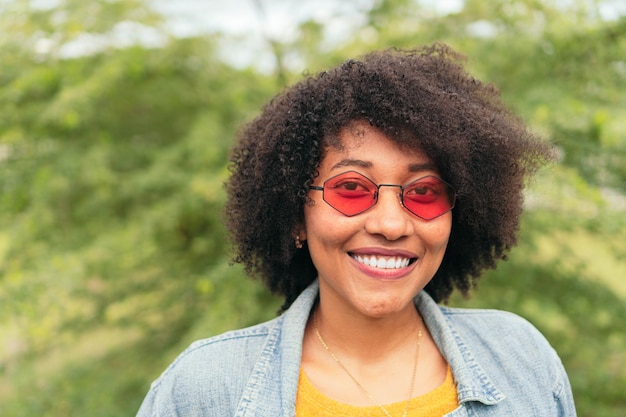 Sonrisa de mujer mientras posa con los brazos cruzados sobre un fondo natural verde