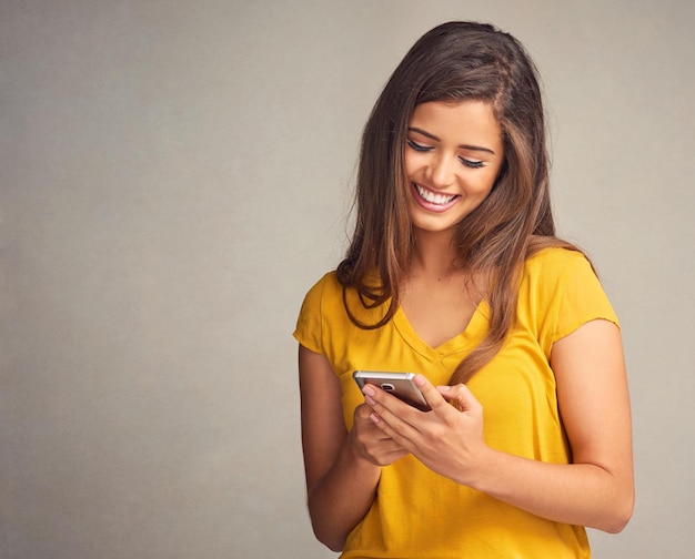 Sonrisa de la mujer y notificación con teléfono inteligente en el fondo del estudio para redes sociales y citas en línea Persona femenina feliz y satisfecha con buenas noticias mensaje de texto y espacio de maqueta