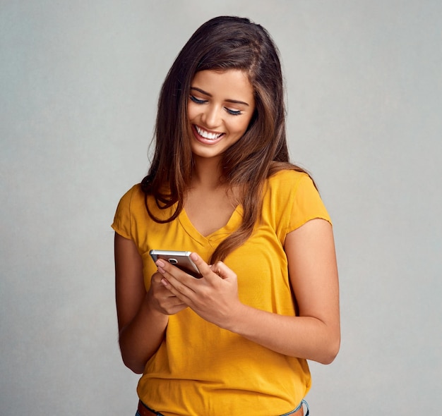 Sonrisa de la mujer y notificación con teléfono inteligente en el fondo del estudio para redes sociales y citas en línea Persona femenina feliz y satisfecha con buenas noticias, mensajes de texto y entretenimiento