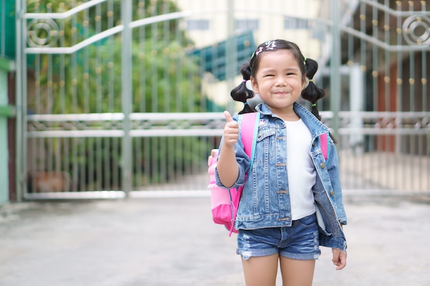 Sonrisa de niña asiática y mochila de hombro de estudiante con diversión feliz y mostrar dedo pulgar para siempre,