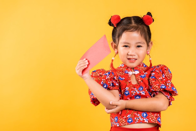 Sonrisa de niña china asiática feliz usar cheongsam rojo qipao sostener angpao paquete rojo regalo monetario