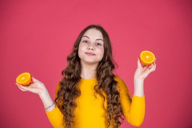 Sonrisa de niño adolescente mantenga fruta naranja sobre fondo rosa