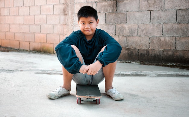 Sonrisa de niño asiático sentado en una patineta Retrato al aire libre de un encantador modelo de niño asiático posando