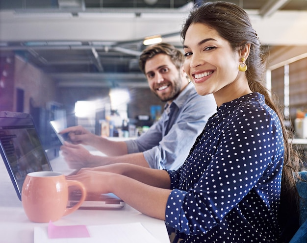 Foto sonrisa de oficina y retrato de un hombre y una mujer en el escritorio con una computadora portátil en una agencia creativa trabajando juntos en un proyecto asociación de liderazgo y empleados felices o socios comerciales en el inicio del diseño