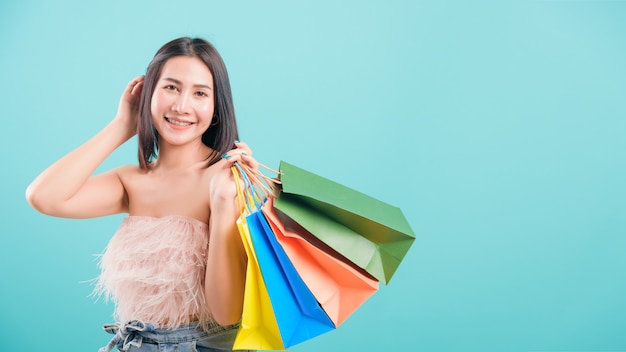 Sonrisa de pie de mujer en compras de verano sosteniendo bolsas de compras multicolores