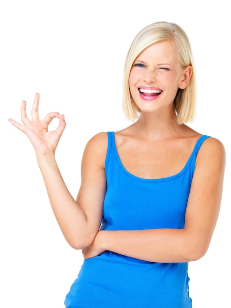 Sonrisa de retrato de mujer feliz y signo OK para satisfacción de aprobación o perfección aislada contra un fondo de estudio blanco Mujer rubia de pie y mostrando gesto de mano bien con guiño por buen trabajo