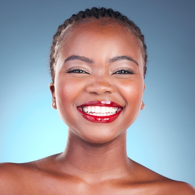 Sonrisa de retrato y mujer negra con maquillaje de belleza natural y brillo en un fondo azul de estudio Rostro de persona y modelo con dermatología estética y bienestar con brillo cosmético y cuidado de la piel