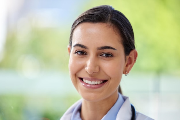 Sonrisa de rostro y mujer feliz en el interior sobre un fondo verde con una actitud positiva de motivación y éxito Retrato de una atractiva mujer joven y feliz de pie sobre un fondo borroso