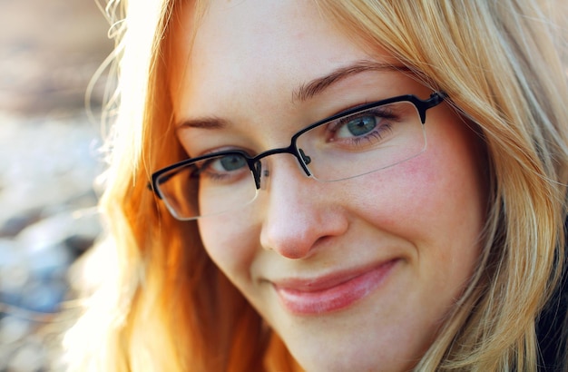 Sonrisa secreta joven mujer rubia con gafas sonriendo a la cámara