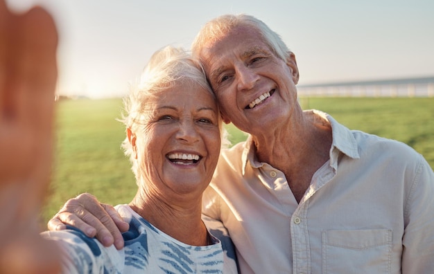 Sonrisa selfie y pareja mayor en la naturaleza para pasar unas vacaciones en Argentina durante su jubilación juntos Sonrisa feliz y retrato de un anciano y una mujer con una foto de vacaciones en un parque