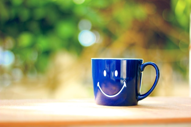 Foto sonrisa en taza azul taza de café contra desenfoque de fondo abstracto bokeh