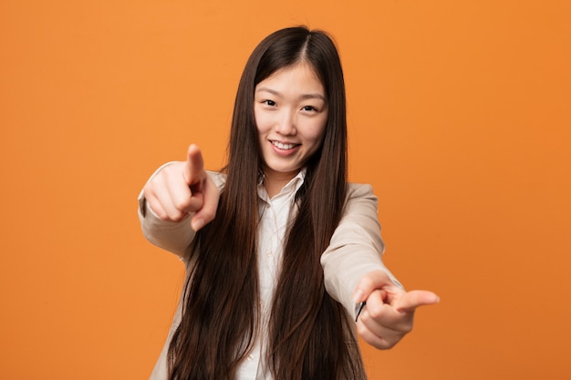 Sonrisas alegres de la mujer china joven del negocio que señalan al frente.