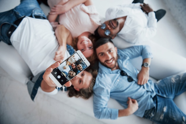 Sonrisas sinceras. Jóvenes que se establecen y se toman una selfie con foco en el teléfono