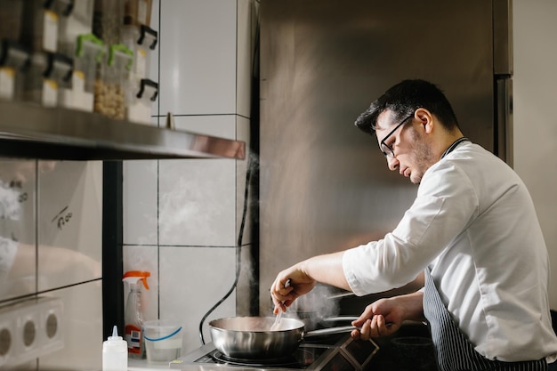 Sooking profissão de comida e conceito de pessoas chef masculino cozinha com frigideira no restaurante kitchenxA