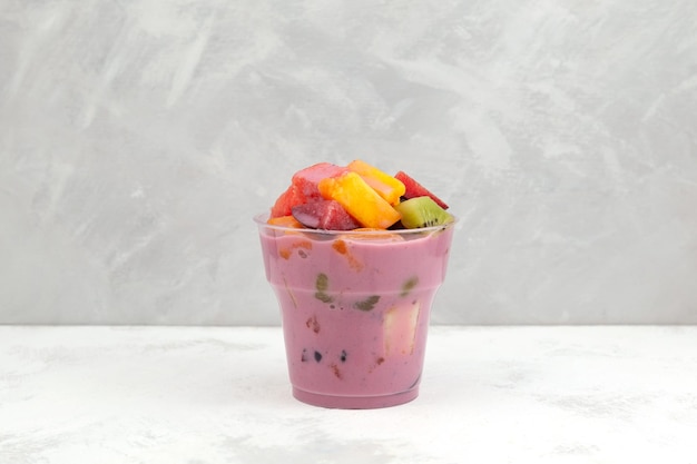 Sop Buah o Es Campur en vaso desechable de plástico para llevar. Ensalada de frutas o cóctel con yogur.