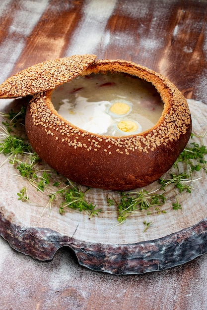 Sopa agria de zurek hecha de harina de centeno con salchicha y huevo servida en un plato de pan Plato popular de Pascua
