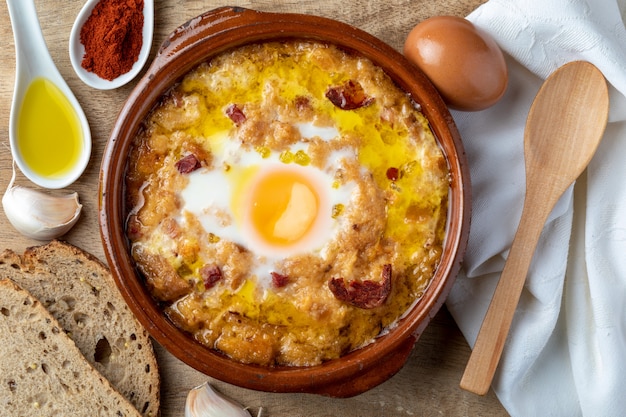 Sopa de ajo y pan (castellano, de España) en cazuela de barro y sus ingredientes principales.