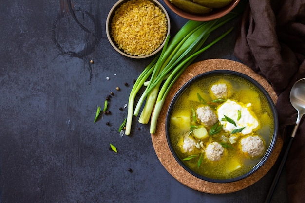 Sopa con albóndigas bulgur y pepinos encurtidos en una mesa de piedra oscura Vista superior Espacio de copia