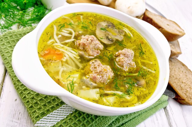 Sopa con albóndigas y fideos en un tazón en una servilleta verde