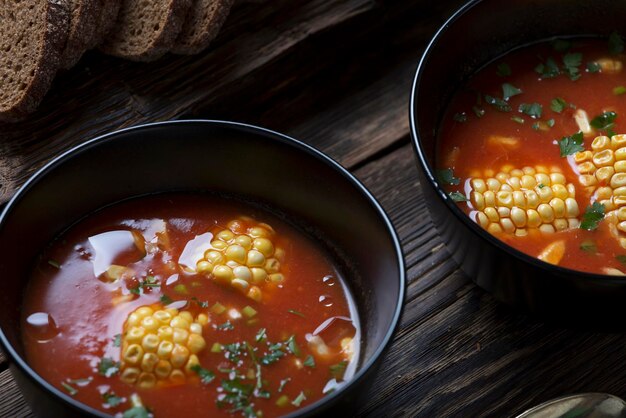 Sopa americana de maíz y tomate en una mesa rústica con pan de centeno