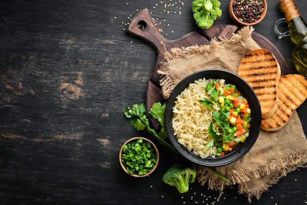 Sopa asiática com macarrão e legumes em uma tigela com pão torrado Comida dietética Vista superior Espaço para cópia grátis