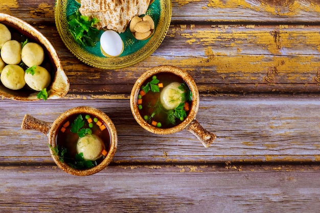 Sopa de bolas de matzá casera en dos platos con cucharas sobre fondo de madera.