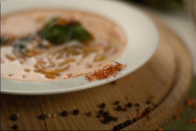 Sopa con brócoli, fideos de arroz y verduras en un soporte de madera