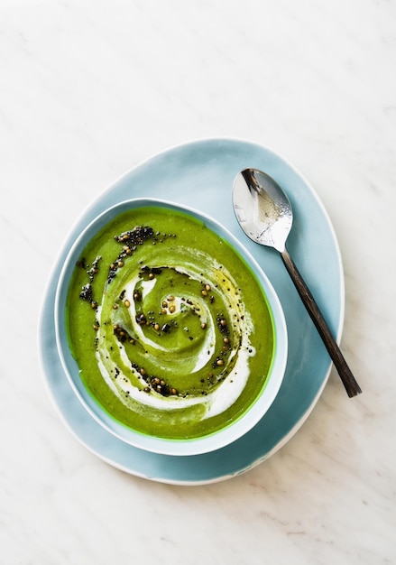 Sopa de brócoli verde con leche de coco y especias picantes fritas sobre mesa de mármol