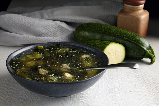 Sopa de calabacín con albóndigas sobre una mesa blanca