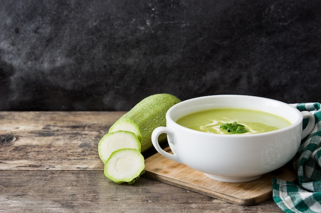 Sopa de calabacín en un tazón sobre mesa de madera y negro