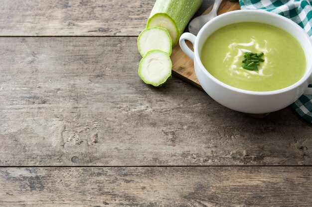 Sopa de calabacín en un tazón sobre mesa de madera y negro